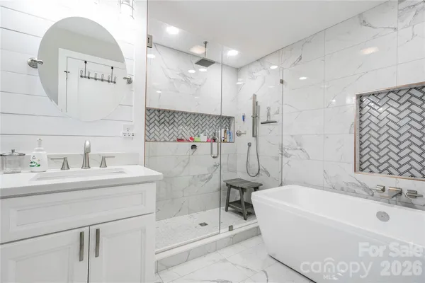 a bathroom with a tub sink shower and mirror
