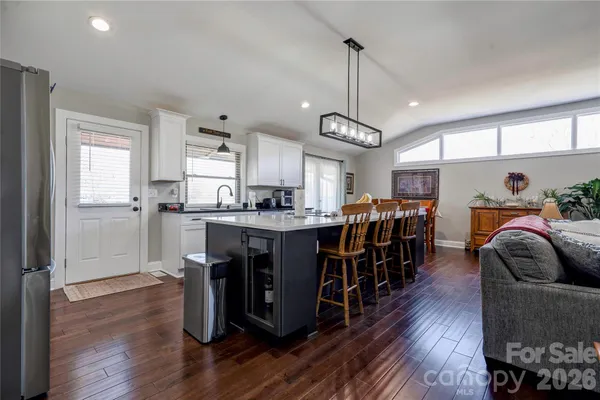 a open kitchen with stainless steel appliances granite countertop a refrigerator a sink dishwasher a dining table and chairs with wooden floor