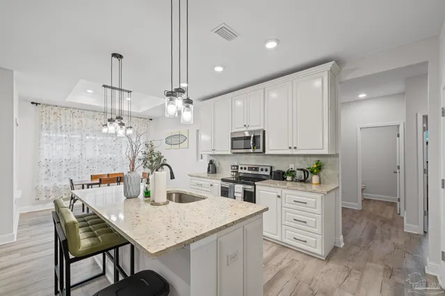 a kitchen with stainless steel appliances kitchen island granite countertop a table chairs and a refrigerator