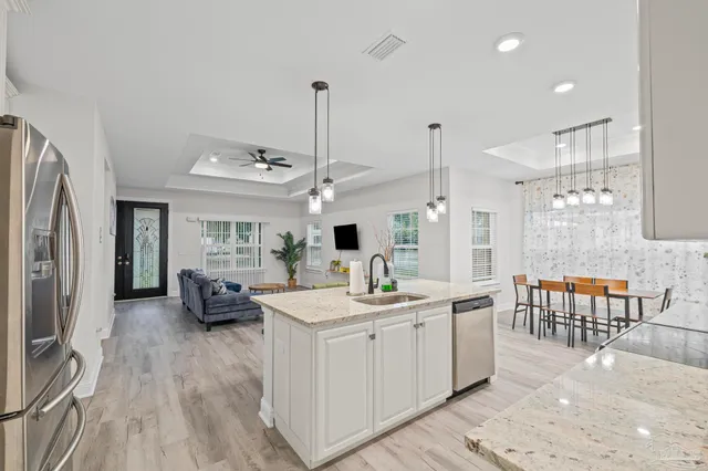 a kitchen with stainless steel appliances kitchen island granite countertop a sink and wooden floor