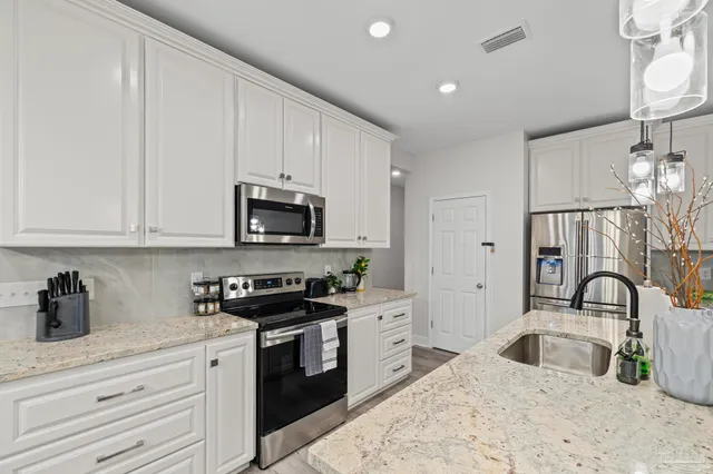 a kitchen with stainless steel appliances a dining table chairs refrigerator and sink