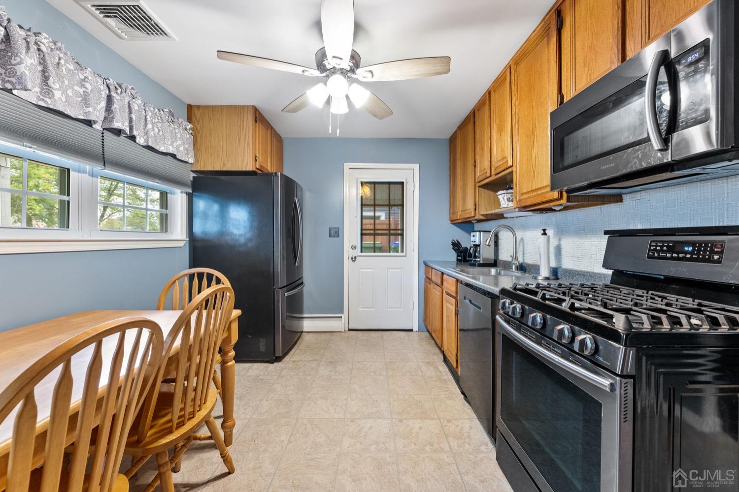 105 Winthrop Road Edison, NJ 08817 - Photo 8 of 33 a kitchen with stainless steel appliances granite countertop a stove top oven a sink a dining table and chairs with wooden floor