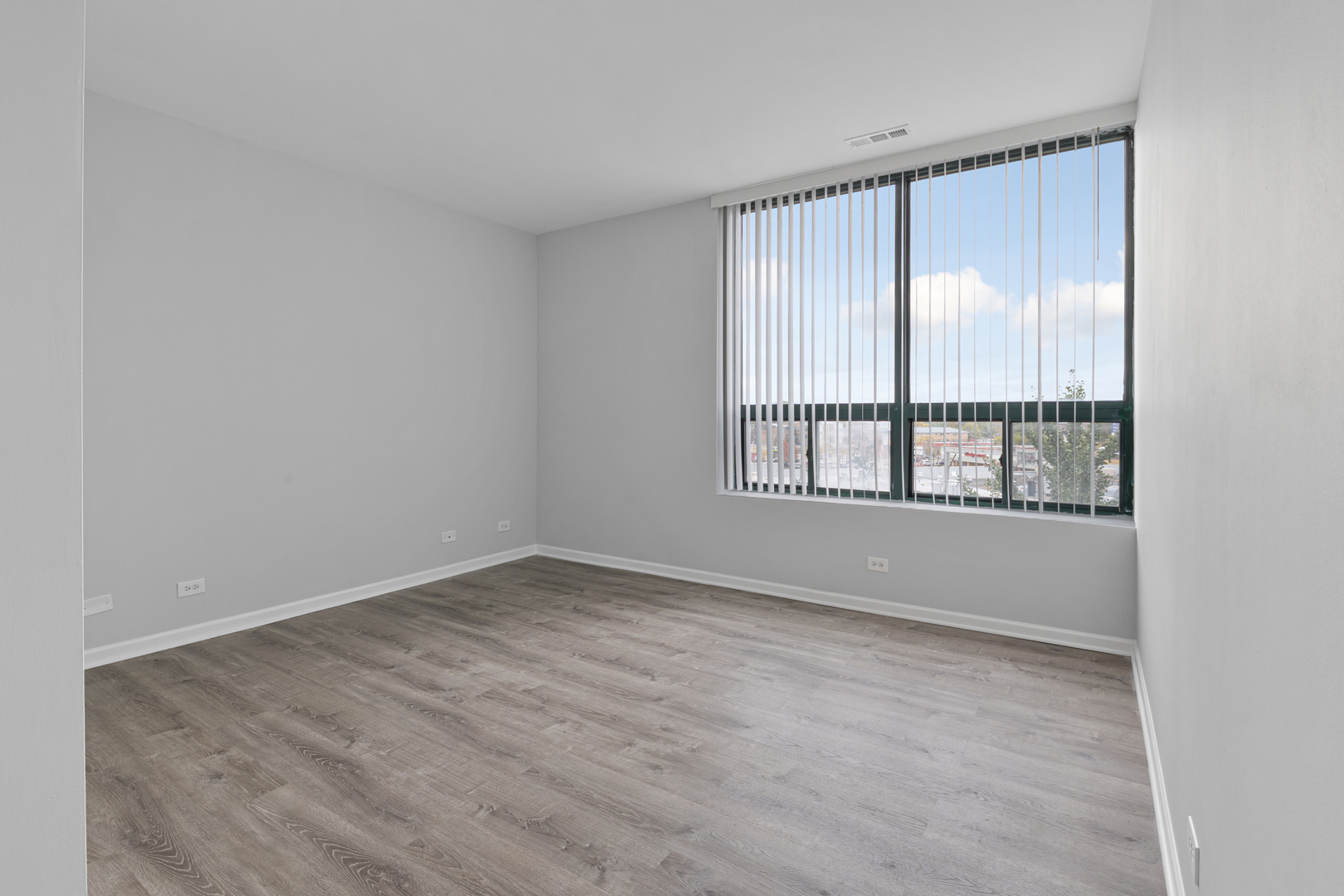 2451 West Howard Street, Unit 406 Chicago, IL 60645 - Photo 6 of 15 an empty room with wooden floor and windows