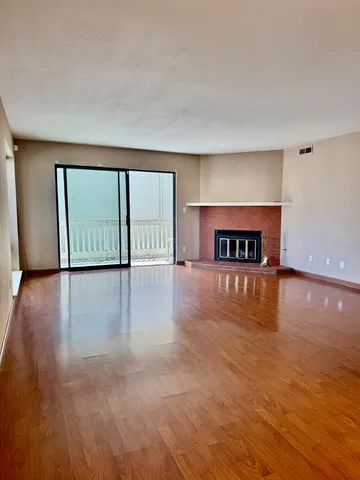 a view of an empty room with window and wooden floor