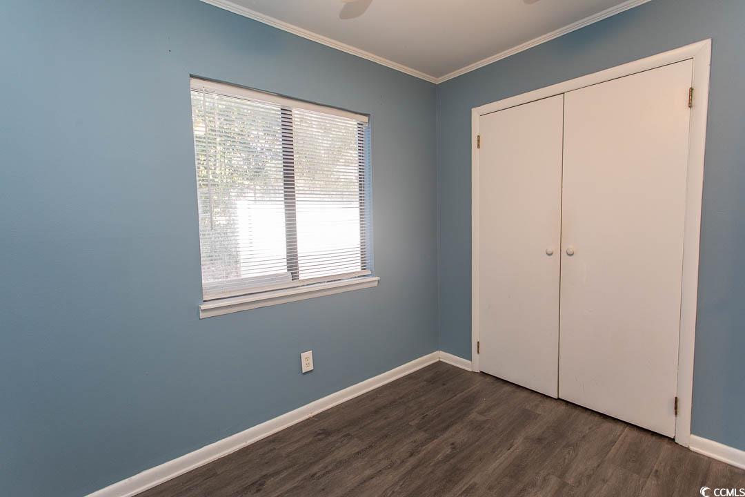 950 Forestbrook Road, Unit C3 Myrtle Beach, SC 29579 - Photo 8 of 19 Unfurnished bedroom with ornamental molding, dark wood-style floors, ceiling fan, and a closet
