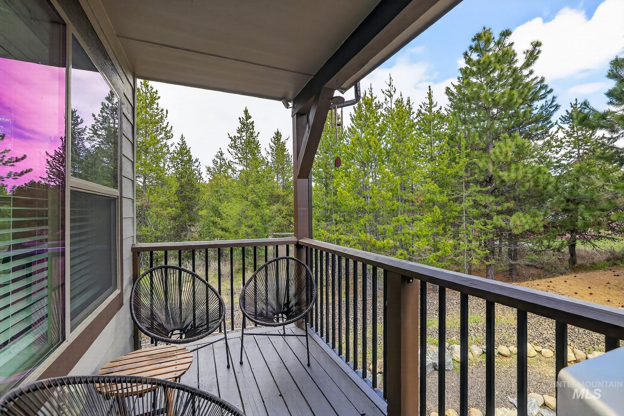 311 Broken Ridge Way McCall, ID 83638 - Photo 13 of 44 Covered balcony with composite decking, black metal railings, and a backdrop of mature evergreen trees