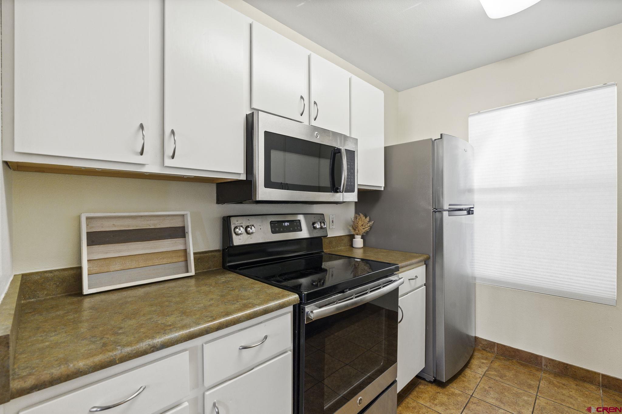 1100 Goeglein Gulch Road, Unit 233 Durango, CO 81301 - Photo 10 of 37 a kitchen with stainless steel appliances white cabinets and a stove a refrigerator with wooden floor