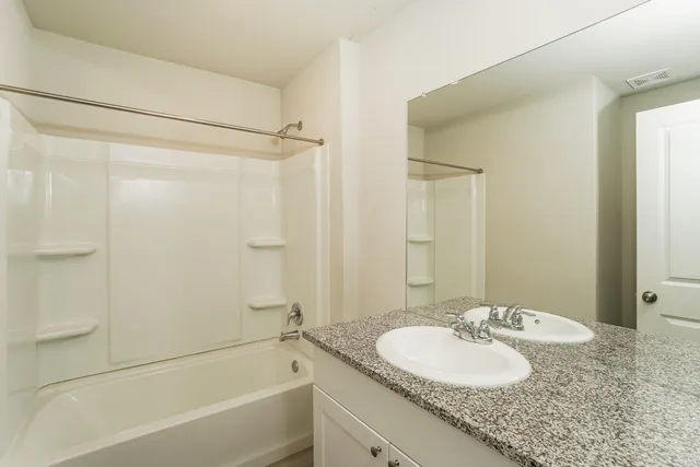 a bathroom with a granite countertop sink mirror and a bathtub