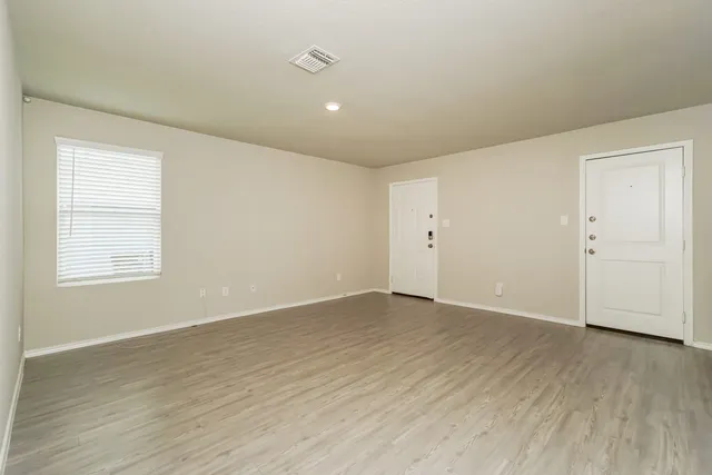 an empty room with wooden floor and windows