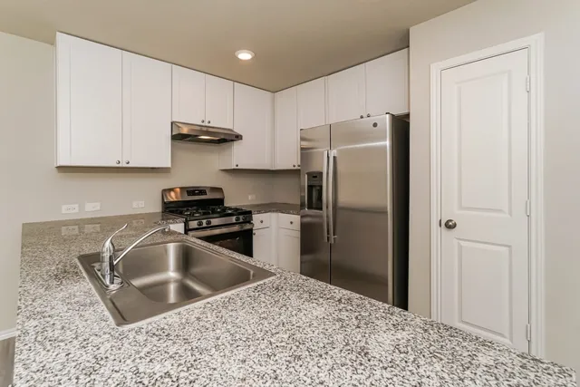 a kitchen with stainless steel appliances granite countertop a sink a refrigerator and a sink
