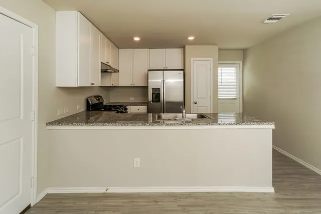 a view of kitchen with granite countertop stainless steel appliances refrigerator sink and stove