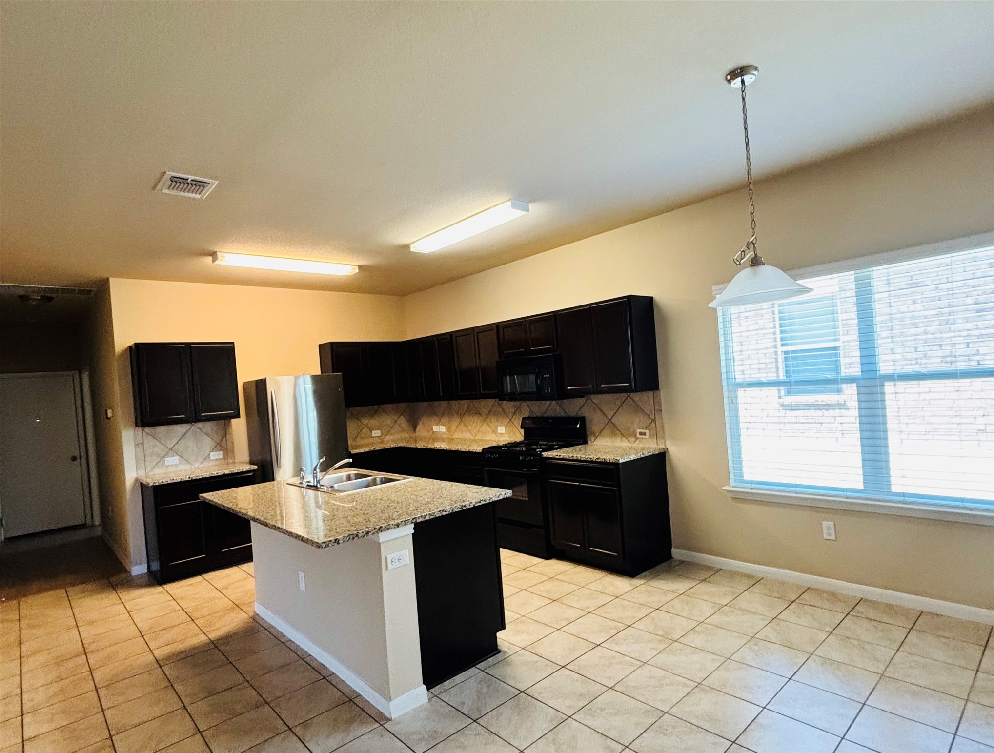 1602 Atlas Road Cedar Park, TX 78613 - Photo 6 of 13 A well-appointed kitchen features dark cabinetry, granite countertops, and tiled flooring.