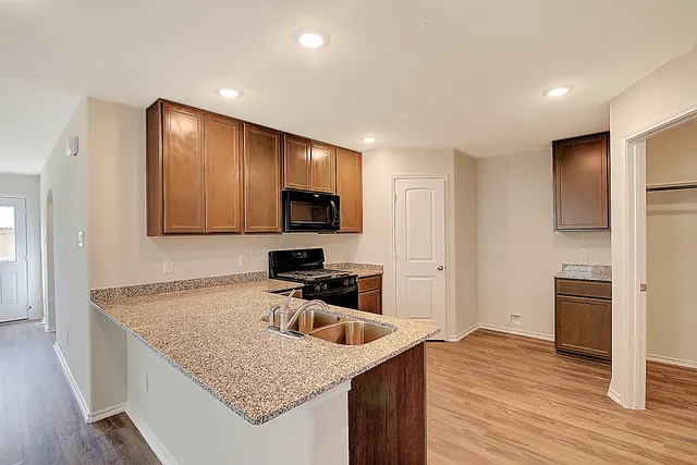 a kitchen with granite countertop a sink a stove and refrigerator