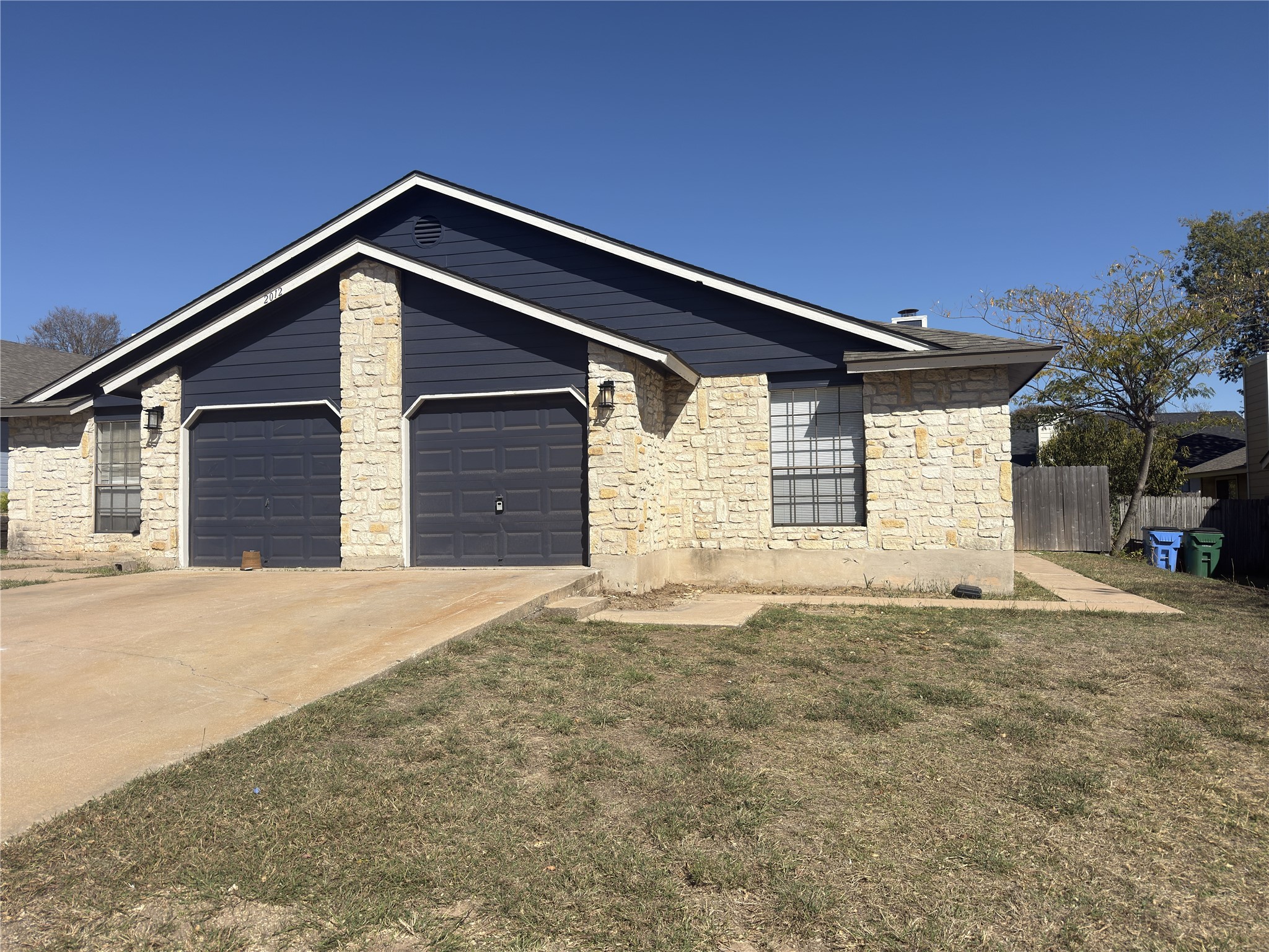 View of front of house with stone siding, driveway, and a garage