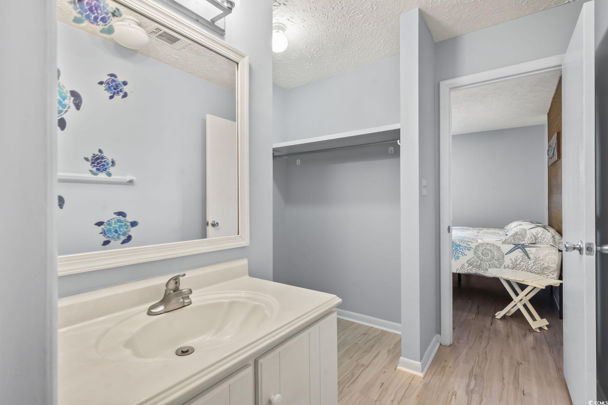 310 5th Avenue North, Unit 206 Surfside Beach, SC 29575 - Photo 19 of 40 Ensuite bathroom with a textured ceiling, vanity, and light wood-style floors