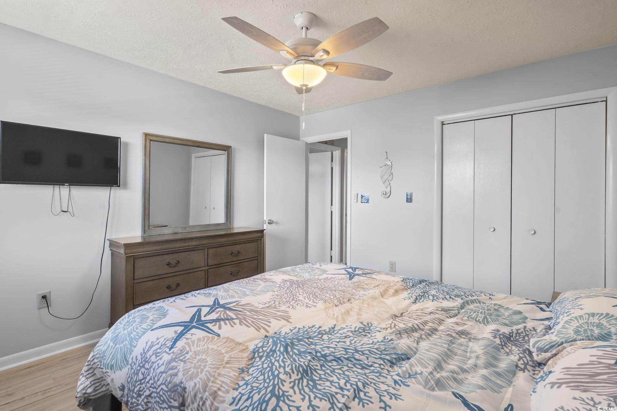 310 5th Avenue North, Unit 206 Surfside Beach, SC 29575 - Photo 27 of 40 Bedroom with a closet, a ceiling fan, wood finished floors, and a textured ceiling