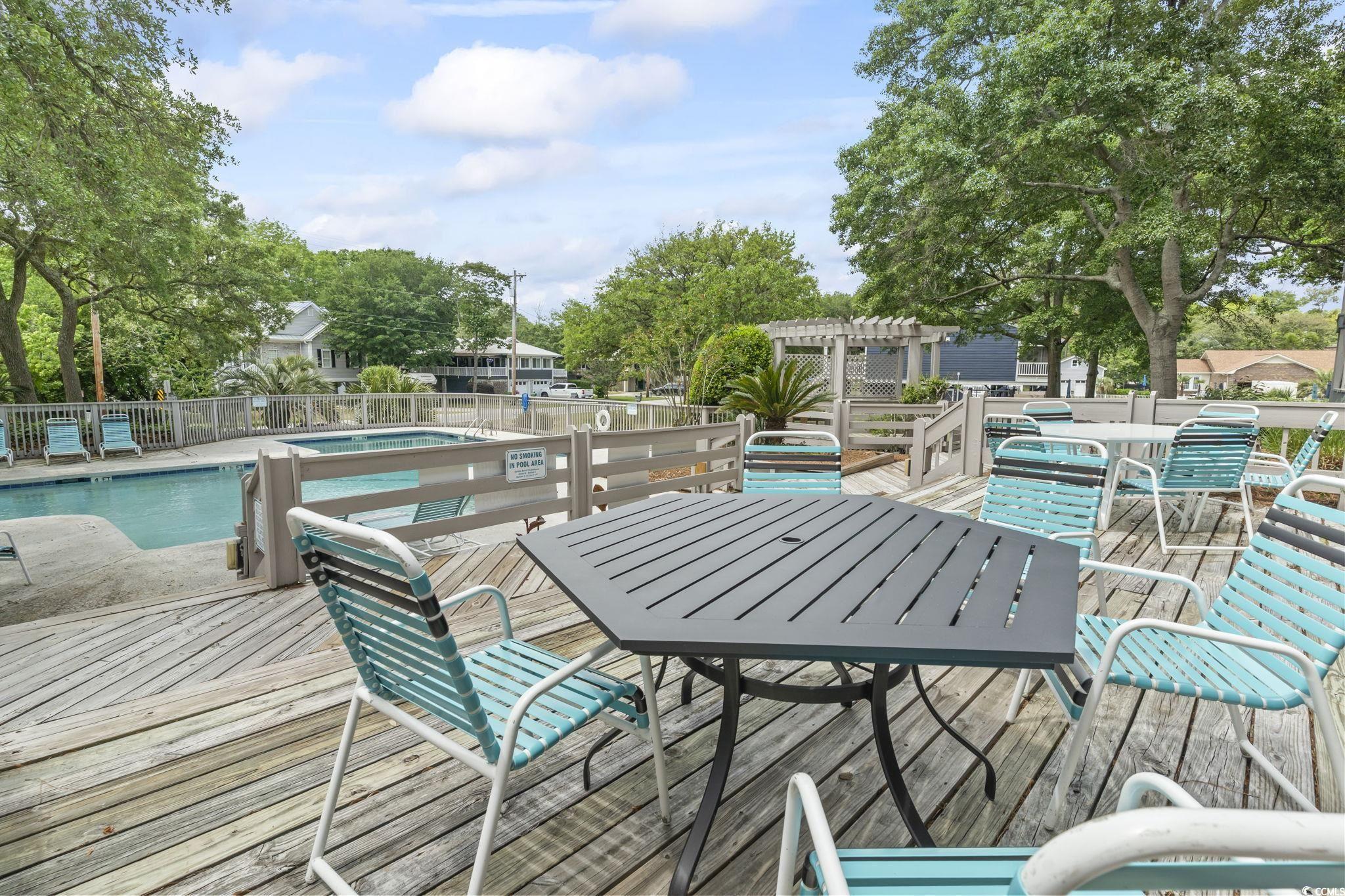 310 5th Avenue North, Unit 206 Surfside Beach, SC 29575 - Photo 39 of 40 Wooden deck with a community pool, a patio area, outdoor dining space, and a pergola