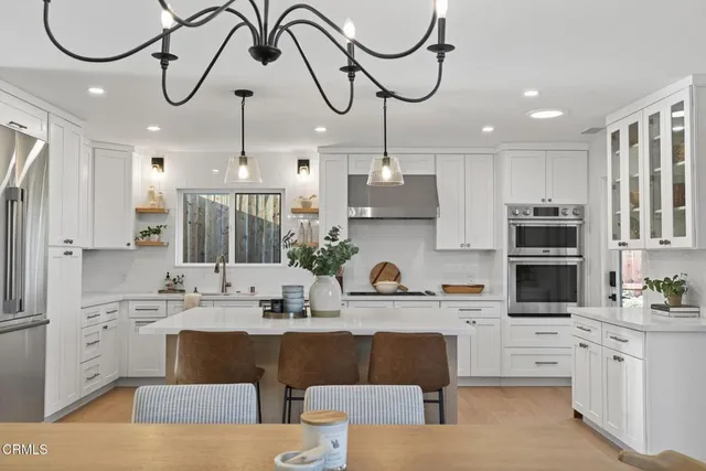 a kitchen with stainless steel appliances a sink a stove a center island and a cabinets