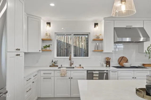 a kitchen with kitchen island granite countertop a refrigerator a sink dishwasher a dining table and chairs with wooden floor