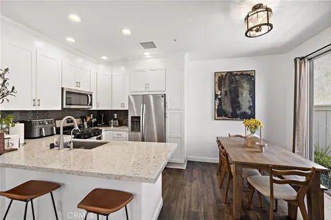a kitchen with stainless steel appliances granite countertop a dining table chairs and refrigerator