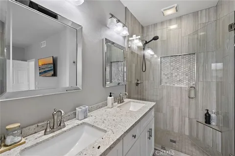 a bathroom with a granite countertop sink a mirror and a shower