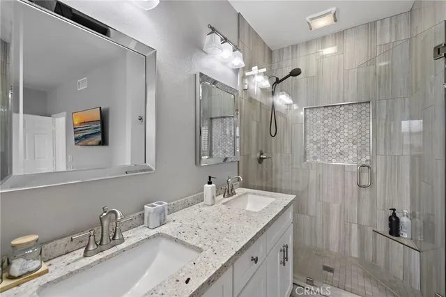 a bathroom with a granite countertop sink a mirror and a shower