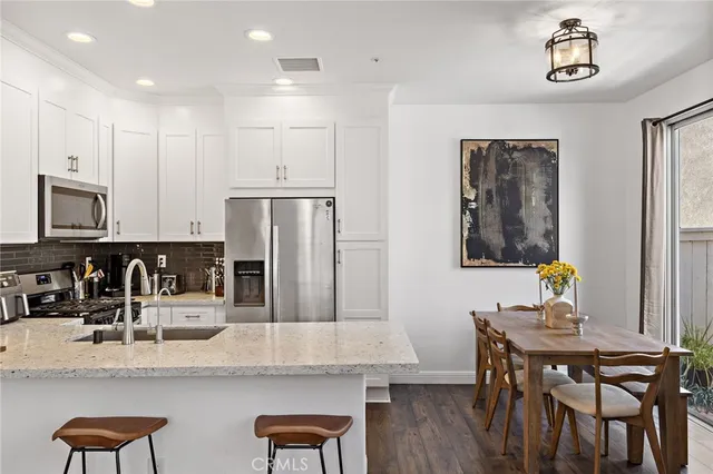 a kitchen with granite countertop a table chairs stove and refrigerator