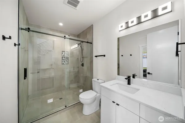 a bathroom with a shower sink mirror and toilet