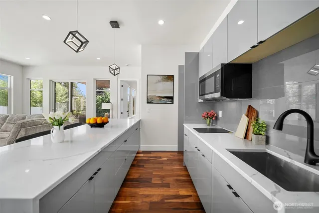 a very nice looking open kitchen with stainless steel appliances granite countertop a sink dishwasher a dining table and chairs with wooden floor