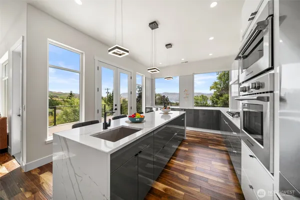 a view of a kitchen with kitchen island a large window cabinets a sink and stainless steel appliances