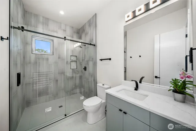 a bathroom with a shower sink vanity mirror and toilet