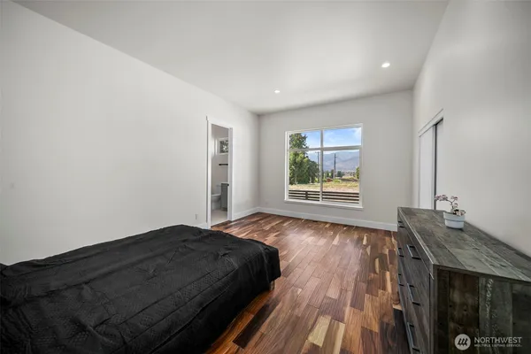 a spacious bedroom with a bed and wooden floor