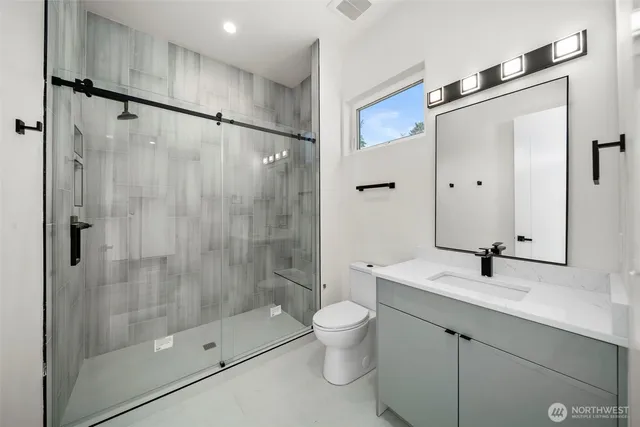 a bathroom with a shower sink vanity mirror and toilet