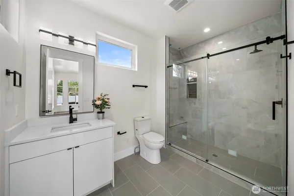 a bathroom with a shower sink vanity mirror and toilet