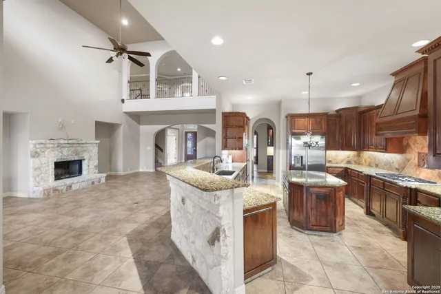 a kitchen with stainless steel appliances granite countertop a stove top oven a sink and a refrigerator