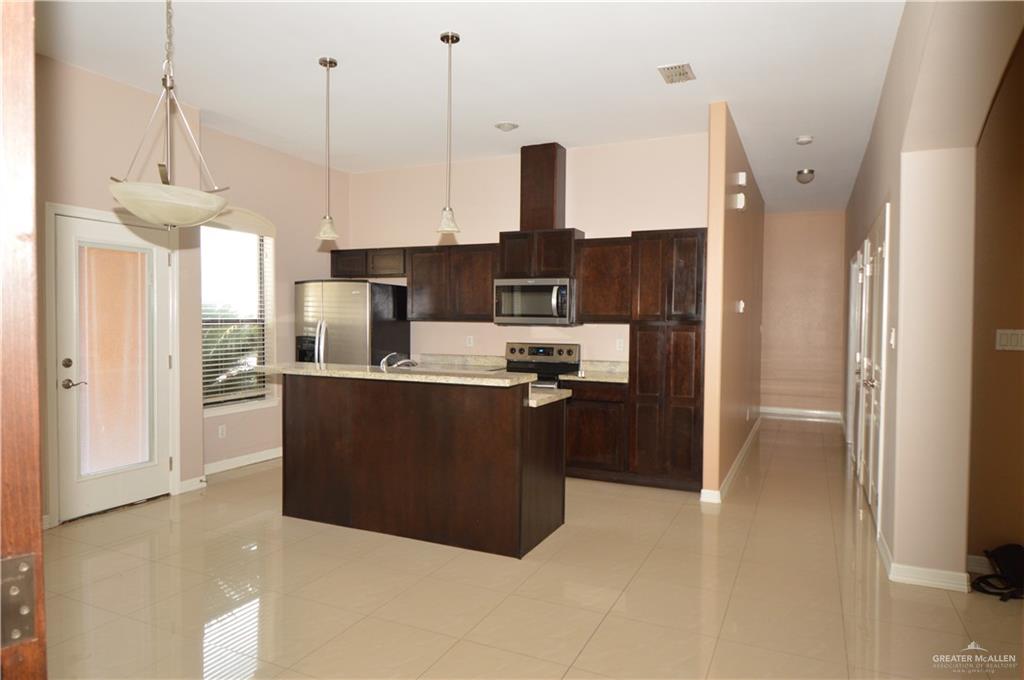 2705 Mimosa Street, Unit 2 Mission, TX 78574 - Photo 11 of 27 Kitchen with pendant lighting, appliances with stainless steel finishes, a kitchen island with sink, light tile patterned flooring, and dark brown cabinetry