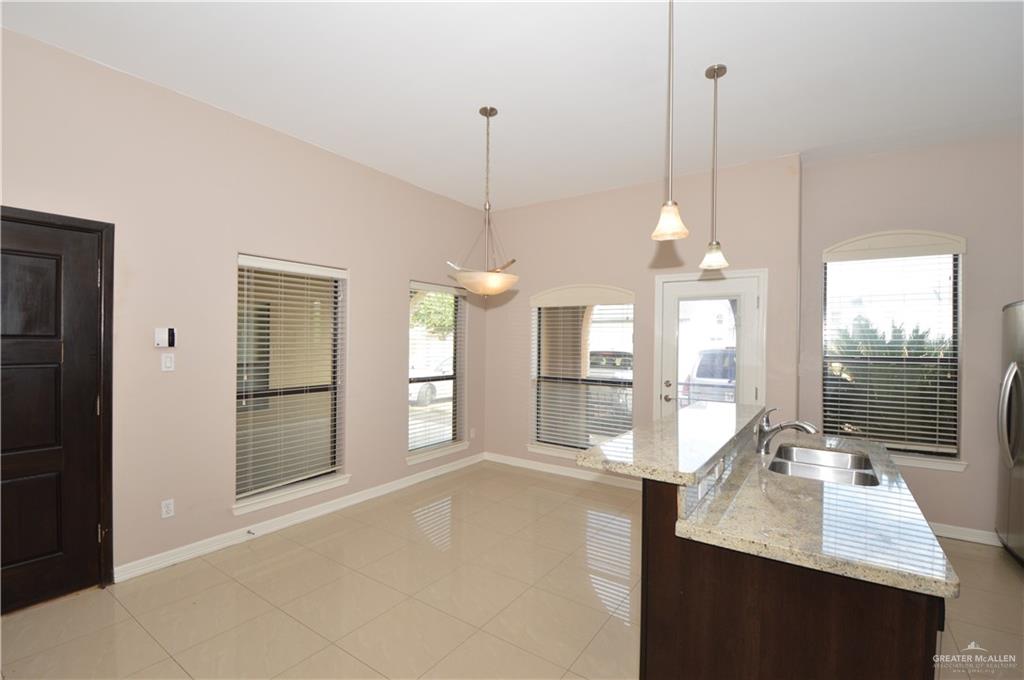2705 Mimosa Street, Unit 2 Mission, TX 78574 - Photo 15 of 27 Kitchen with light stone counters, light tile patterned floors, dark brown cabinetry, an island with sink, and hanging light fixtures