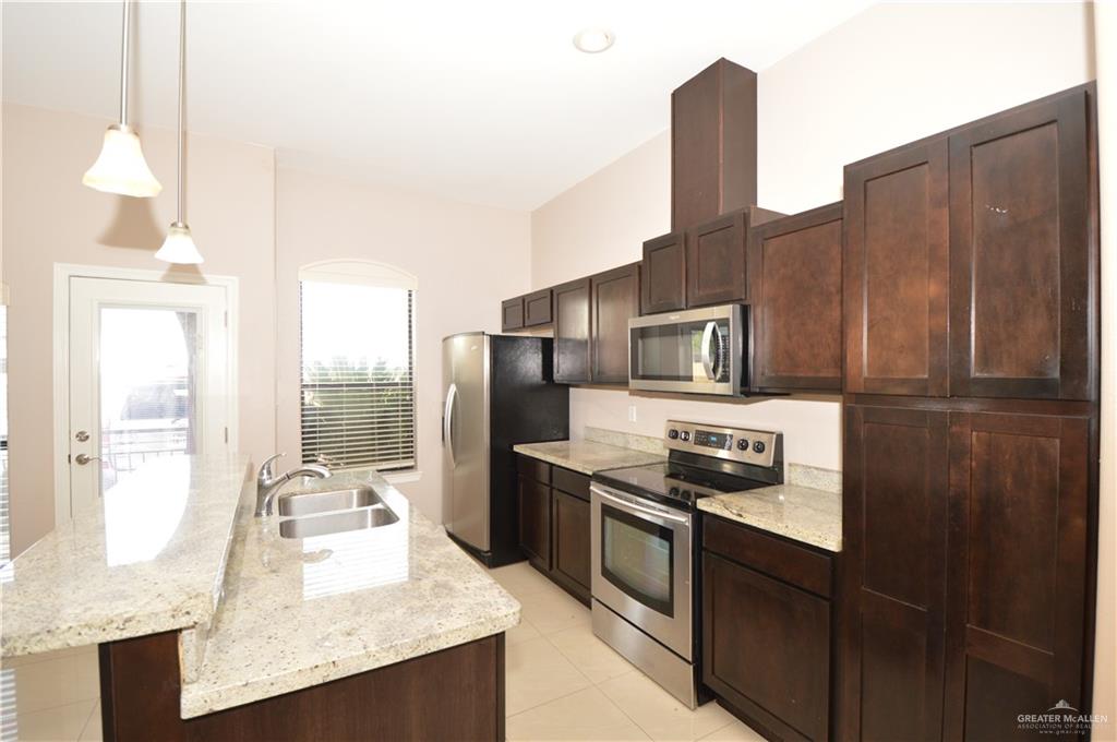 2705 Mimosa Street, Unit 2 Mission, TX 78574 - Photo 16 of 27 Kitchen with appliances with stainless steel finishes, dark brown cabinets, a center island with sink, and decorative light fixtures