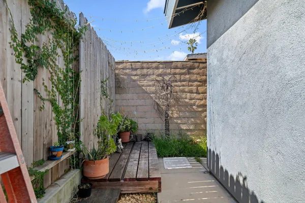 a view of a house with plants and wooden fence