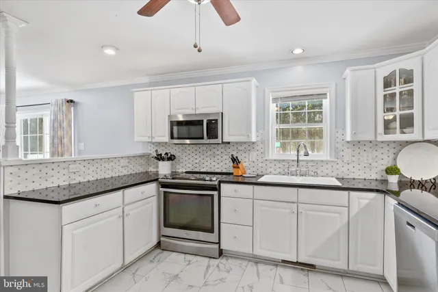a kitchen with stainless steel appliances granite countertop a dining table chairs and a refrigerator