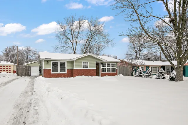 a front view of a house with a yard covered in snow