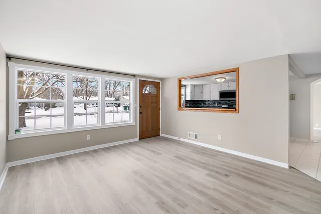 a view of an empty room with a window and wooden floor