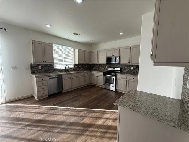 a kitchen with stainless steel appliances granite countertop a stove a sink and a microwave