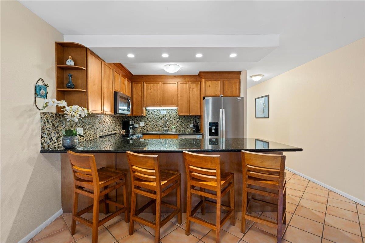 2695 South Kihei Road, Unit 6109 Kihei, HI 96753 - Photo 5 of 49 a kitchen with stainless steel appliances kitchen island granite countertop a refrigerator and microwave