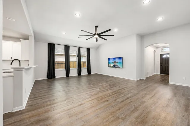 a view of an empty room with a window and a kitchen