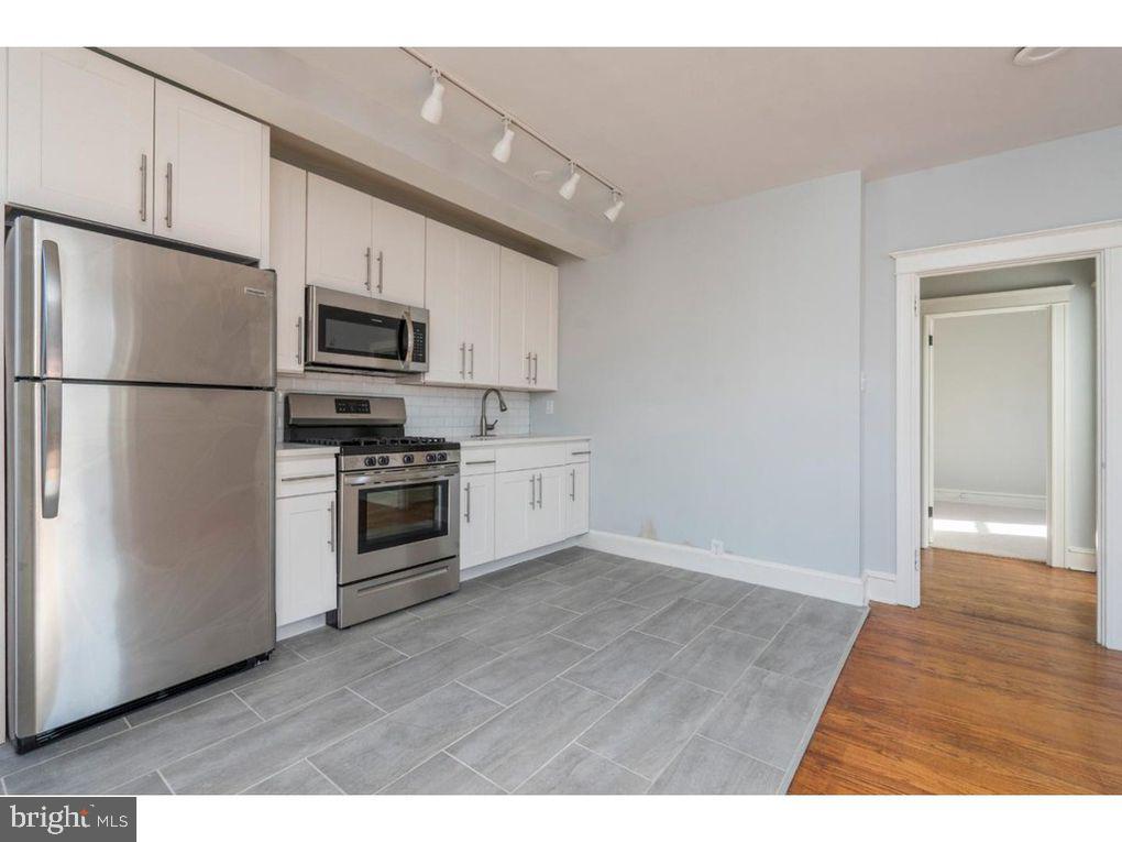 320 Rochelle Avenue, Unit 32 Philadelphia, PA 19128 - Photo 7 of 19 a kitchen with kitchen island a white cabinets and stainless steel appliances