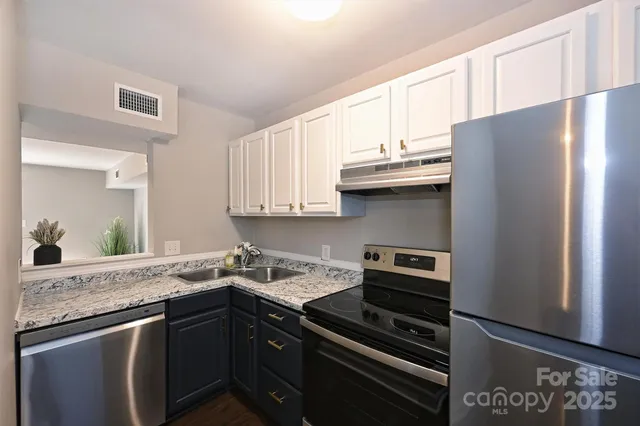 a kitchen with granite countertop a refrigerator stove and sink