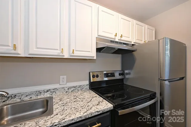 a kitchen with granite countertop a stove sink and refrigerator