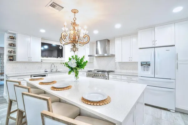 a kitchen with kitchen island granite countertop a white cabinets a stove a dining table and chairs