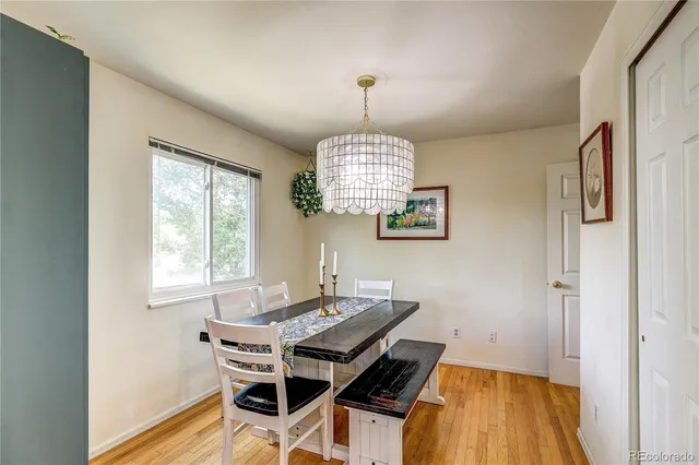 a dining room with wooden floor a chandelier a wooden table and chairs